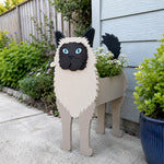 Birman cat planter filled with fresh flowers is placed in the garden