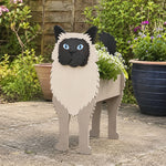 Birman cat planter filled with fresh flowers is placed in the garden