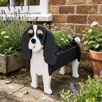 Cavalier King Charles Spaniel dog planter filled with fresh flowers is placed in the garden.