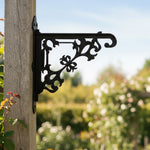 Classic baroque scrollwork metal hanging basket bracket mounted on outdoor wall for plant decoration