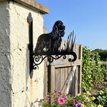 Cocker spaniel metal hanging basket bracket mounted on outdoor wall for plant decoration