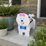 Coton de Tulear dog planter filled with fresh flowers is placed in the garden