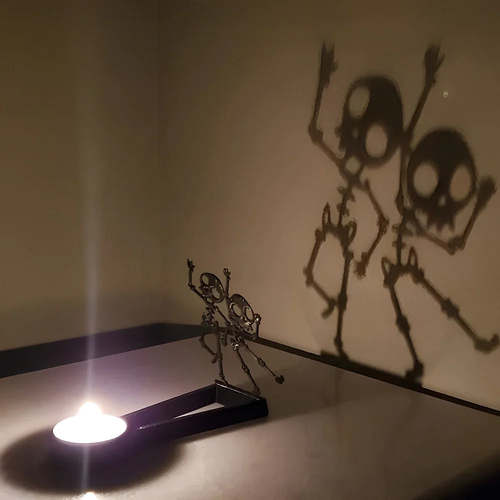 Dancing skeletons halloween metal candle holder casting a spooky shadow on the wall