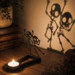 Dancing skeletons halloween metal candle holder casting a spooky shadow on the wall