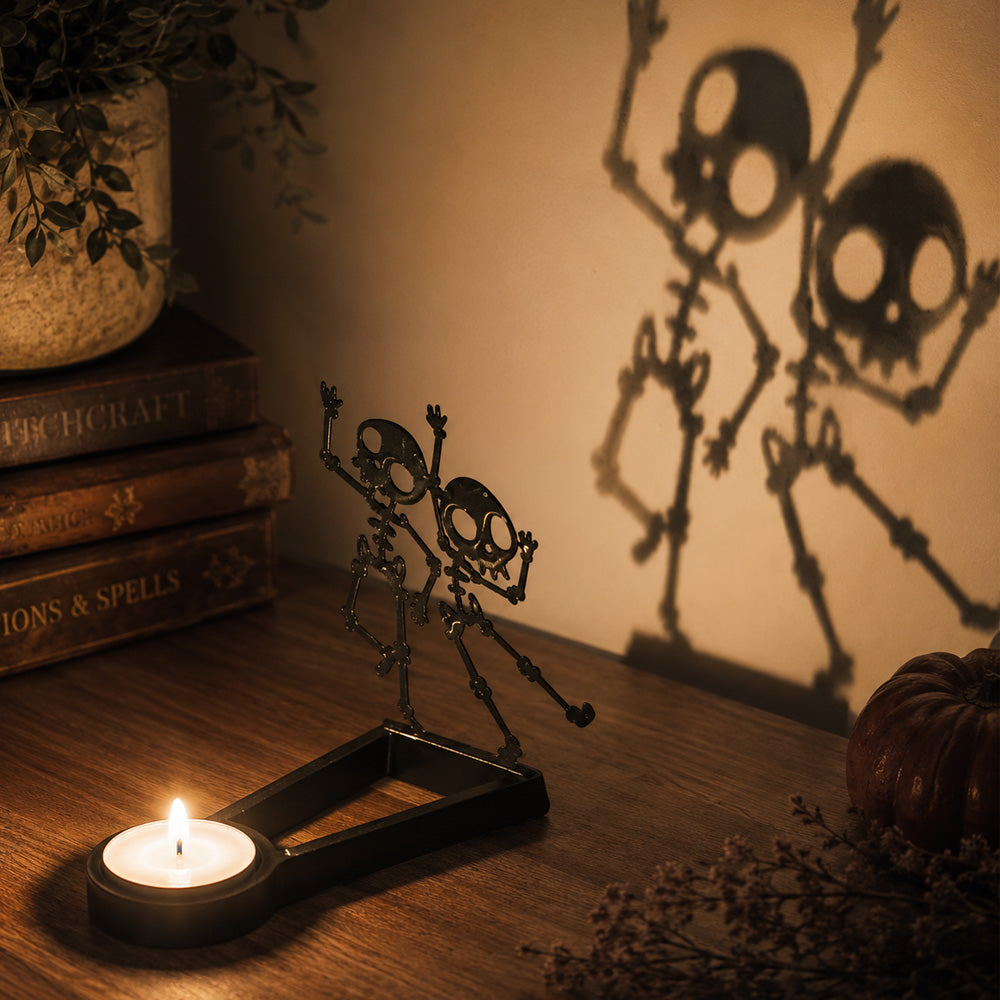 Dancing skeletons halloween metal candle holder casting a spooky shadow on the wall