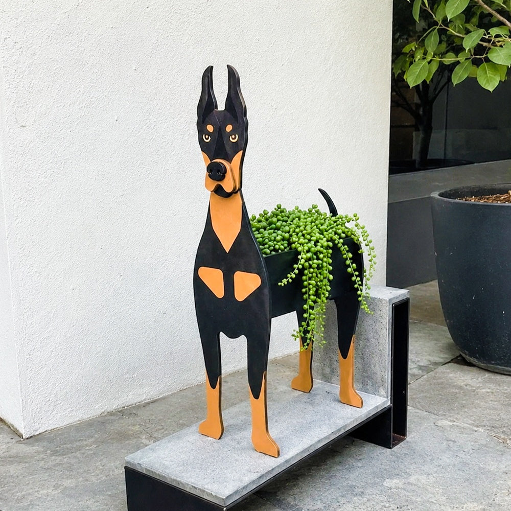 Doberman dog planter filled with fresh flowers is placed in the garden.