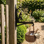 Garden gnome under tree metal hanging basket bracket mounted on outdoor wall for plant decoration