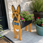 German Shepherd dog planter filled with fresh flowers is placed in the garden.