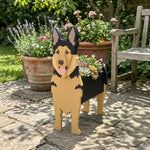 German Shepherd dog planter filled with fresh flowers is placed in the garden.