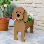 Goldendoodle dog planter filled with fresh flowers is placed in the garden