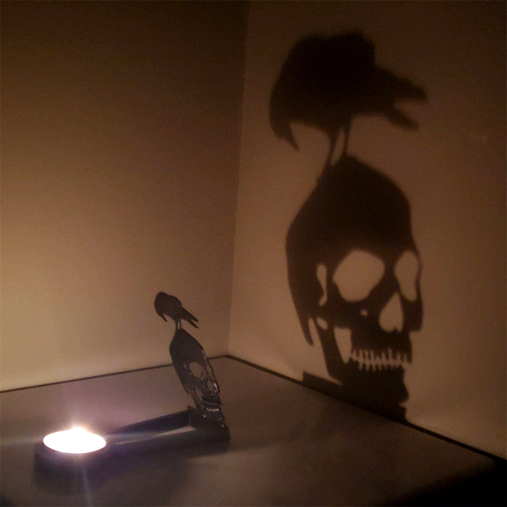Graveyard skull halloween metal candle holder casting a spooky shadow on the wall