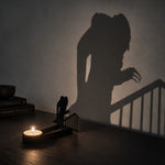 Hunched zombie halloween metal candle holder casting a spooky shadow on the wall