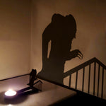 Hunched zombie halloween metal candle holder casting a spooky shadow on the wall