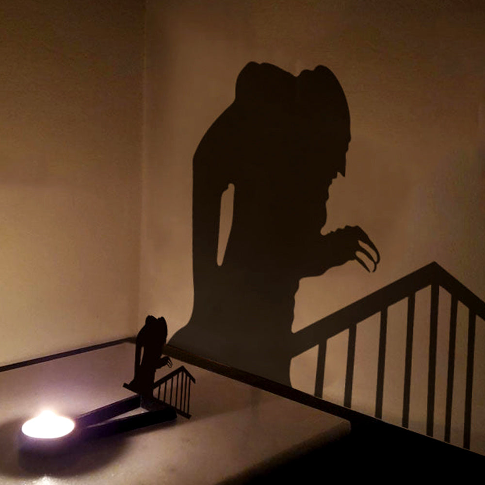 Hunched zombie halloween metal candle holder casting a spooky shadow on the wall