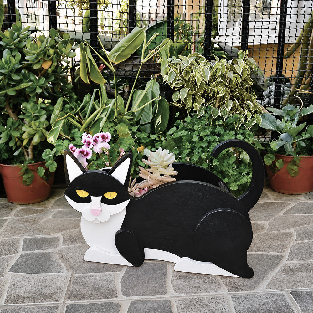 Lying cats planter filled with fresh flowers is placed in the garden