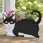 Lying cats planter filled with fresh flowers is placed in the garden