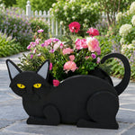 Lying cats planter filled with fresh flowers is placed in the garden