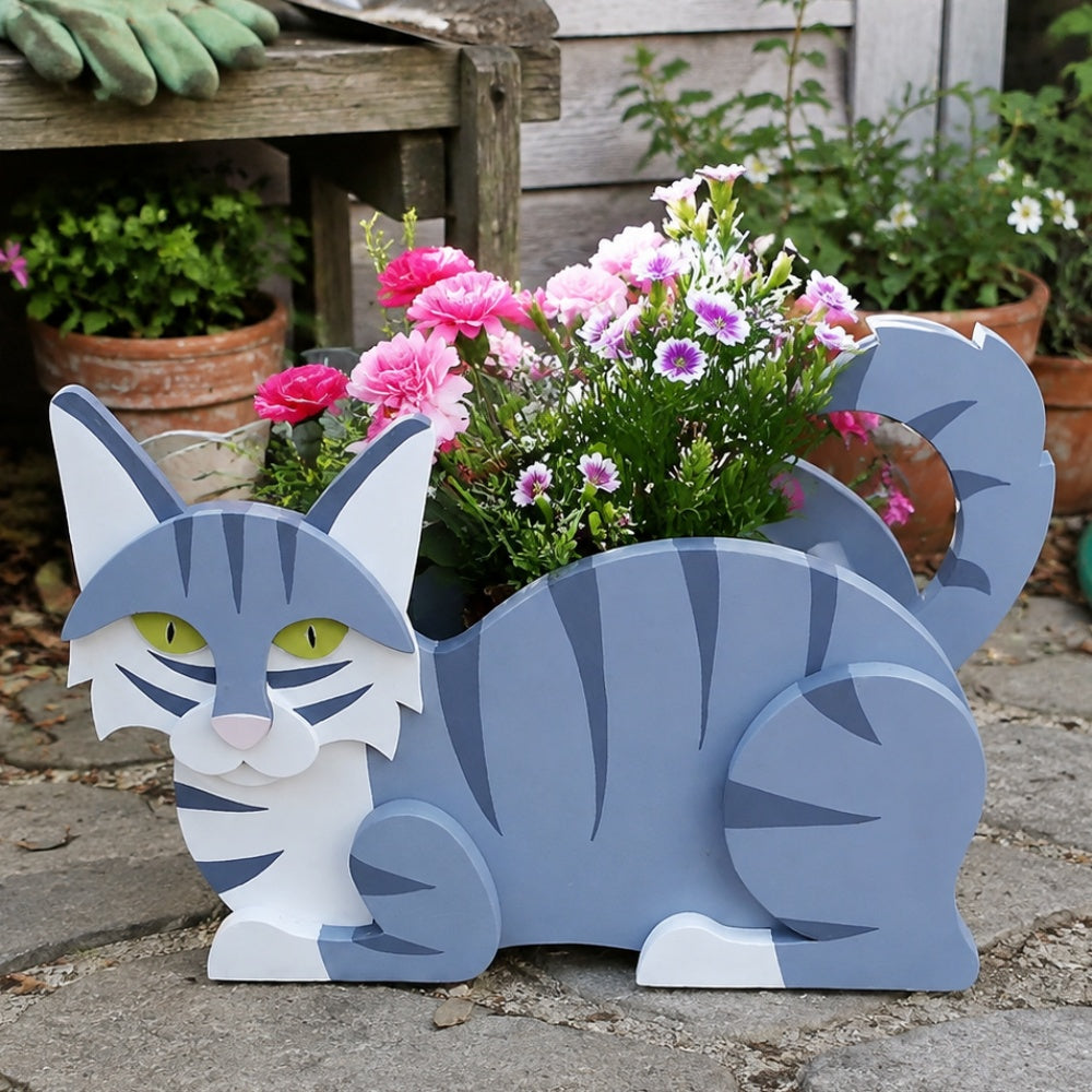 Lying cats planter filled with fresh flowers is placed in the garden