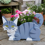 Lying cats planter filled with fresh flowers is placed in the garden