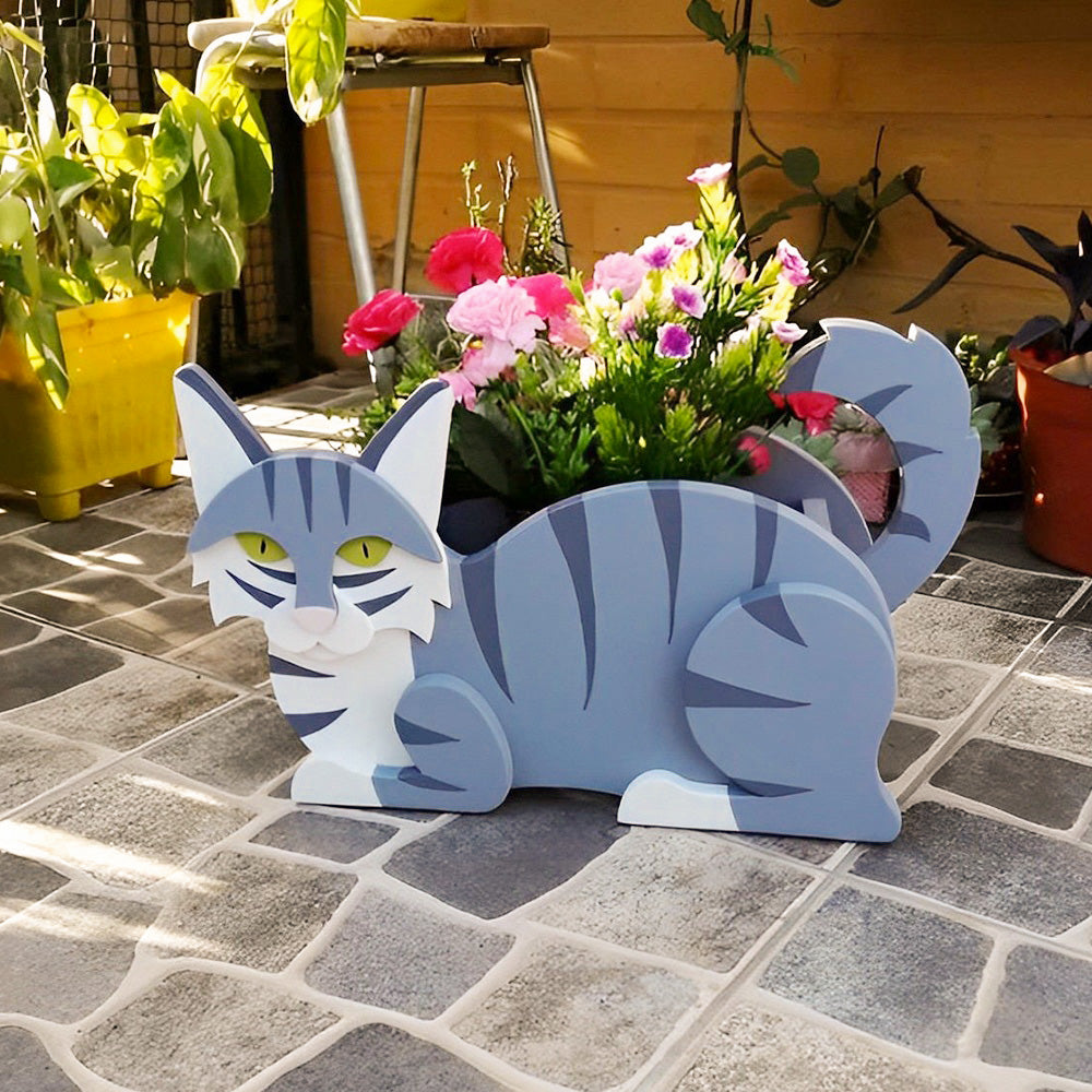 Lying cats planter filled with fresh flowers is placed in the garden