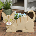 Lying cats planter filled with fresh flowers is placed in the garden
