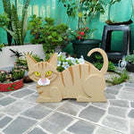 Lying cats planter filled with fresh flowers is placed in the garden
