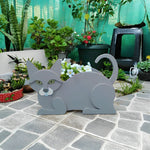 Lying cats planter filled with fresh flowers is placed in the garden
