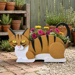 Lying cats planter filled with fresh flowers is placed in the garden