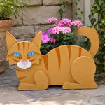Lying cats planter filled with fresh flowers is placed in the garden