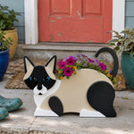 Lying cats planter filled with fresh flowers is placed in the garden