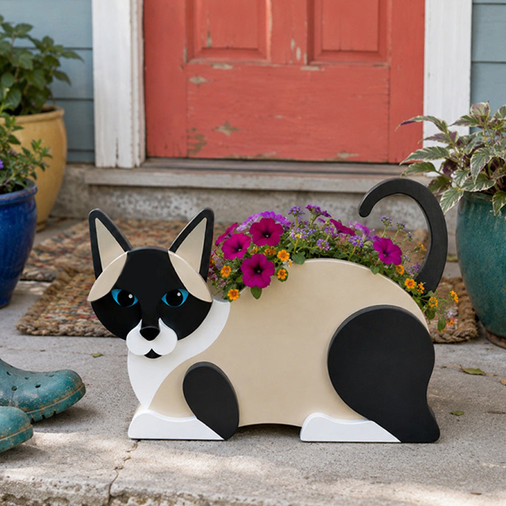 Lying cats planter filled with fresh flowers is placed in the garden
