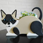 Lying cats planter filled with fresh flowers is placed in the garden