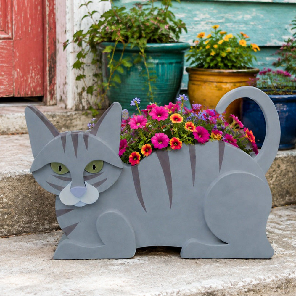 Lying cats planter filled with fresh flowers is placed in the garden