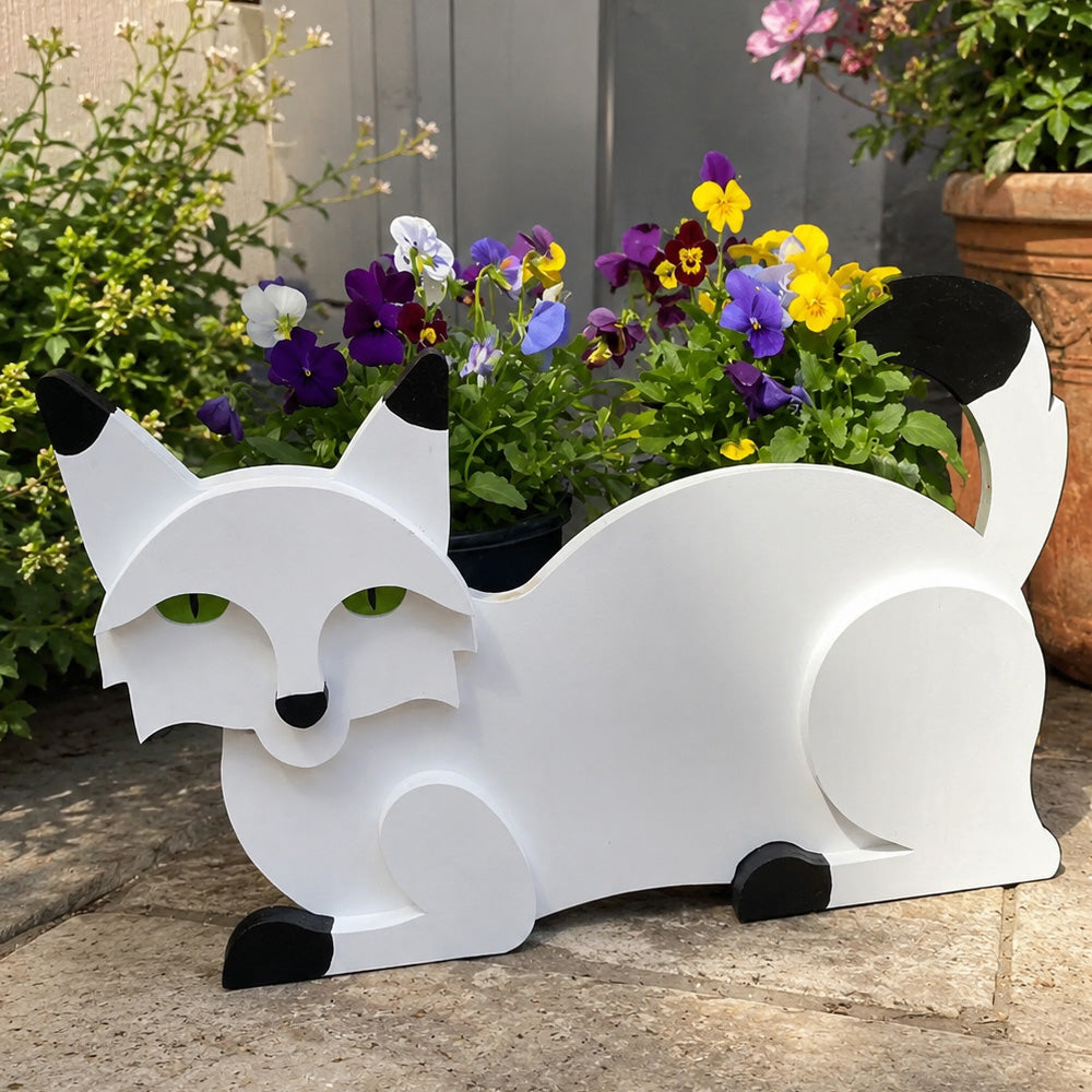 Lying cats planter filled with fresh flowers is placed in the garden
