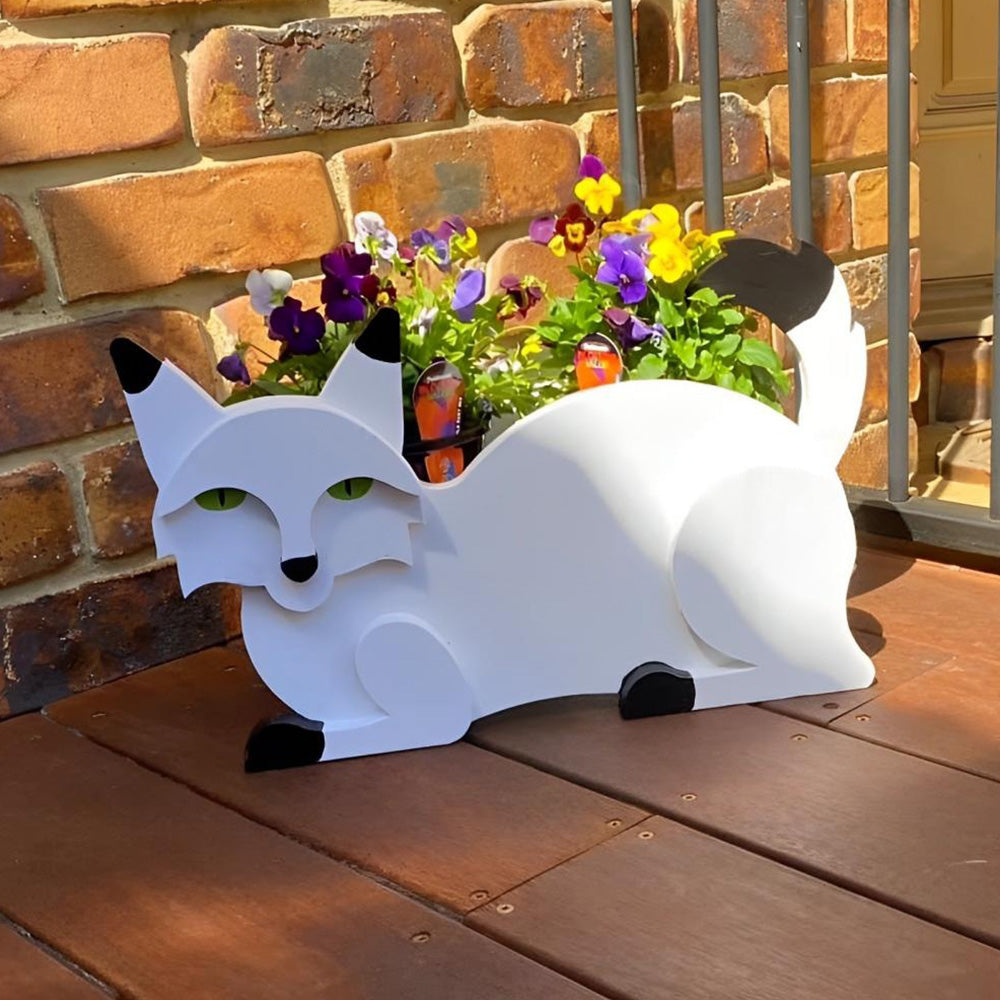 Lying cats planter filled with fresh flowers is placed in the garden