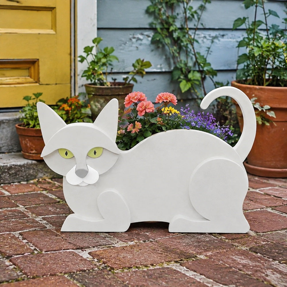Lying cats planter filled with fresh flowers is placed in the garden