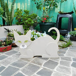Lying cats planter filled with fresh flowers is placed in the garden
