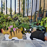 Lying cats planter filled with fresh flowers is placed in the garden