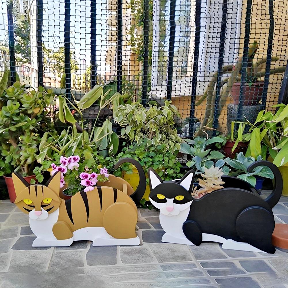 Lying cats planter filled with fresh flowers is placed in the garden