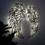 Black metal angel wings wall art displayed on a living room wall