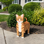 Orange Tabby cat planter filled with fresh flowers is placed in the garden