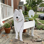 Samoyed dog planter filled with fresh flowers is placed in the garden