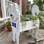 Samoyed dog planter filled with fresh flowers is placed in the garden