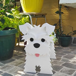 Schnauzer dog planter filled with fresh flowers is placed in the garden