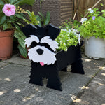 Schnauzer dog planter filled with fresh flowers is placed in the garden