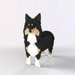 Sheltie-Shetland Sheepdog planter filled with fresh flowers is placed in the garden