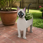 Siamese cat planter filled with fresh flowers is placed in the garden