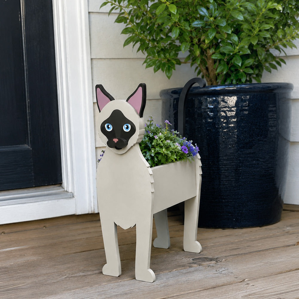 Siamese cat planter filled with fresh flowers is placed in the garden