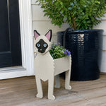 Siamese cat planter filled with fresh flowers is placed in the garden
